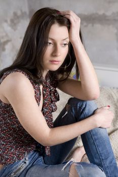 young attractive serious woman in jeans having hole sitting on stairs. Woman`s problem

