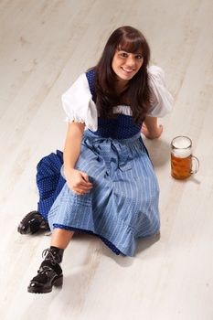 sitting bavarian girl in a costume with a beer mug