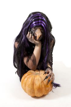girl dressed up as a witch leaning on a pumpkin