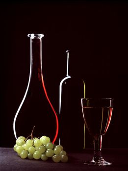 Bottles with wine, a glass and grapes cluster