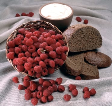Fresh raspberry in a basket with bread and sour cream