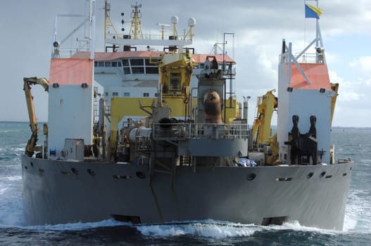 A dredger ship works in the bay moving dirt from the bottom of the water.