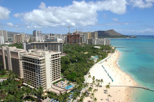 Looking out across Waikiki Beach to Diamond Head with sunbathers enjoying the sand and surf.