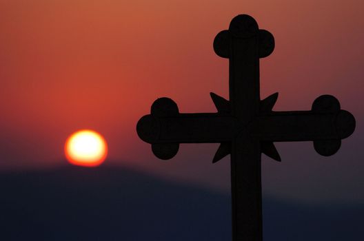 The vision of a cross is seen against the backdrop of the sun setting in Greece.