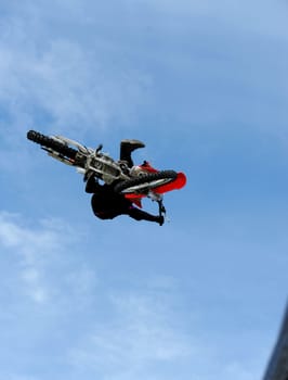 A male motox rider flies through the air doing a trick.