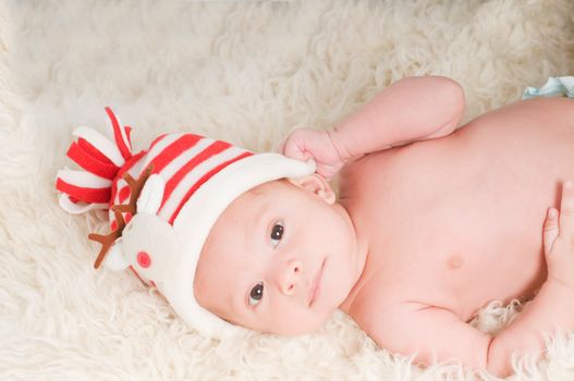 Newborn baby in chritstmas hat lies on fur