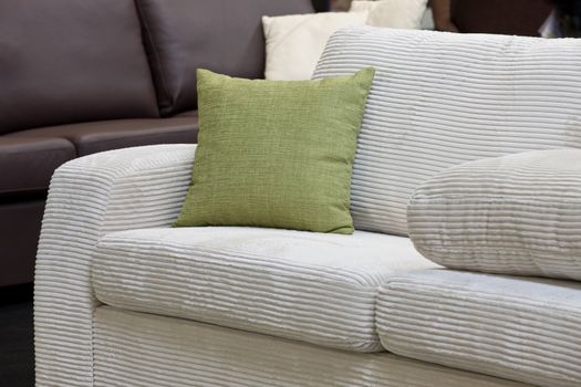 Green pillow on the white velveteen sofa