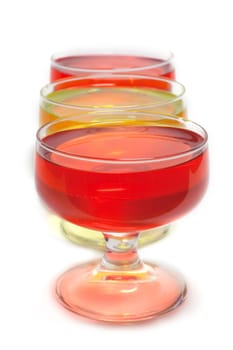 Yellow, red jelly in transparent glass stand on white background inline