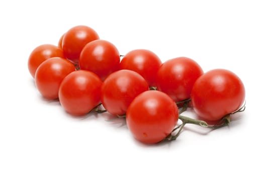 Red tomatoes cherry on green branch insulated on white background