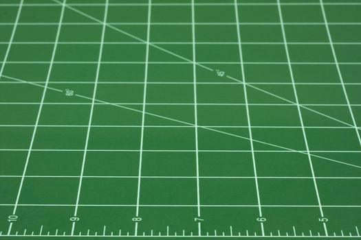 green self healing cutting mat with grid of white converging lines, focus on inch ruler in front