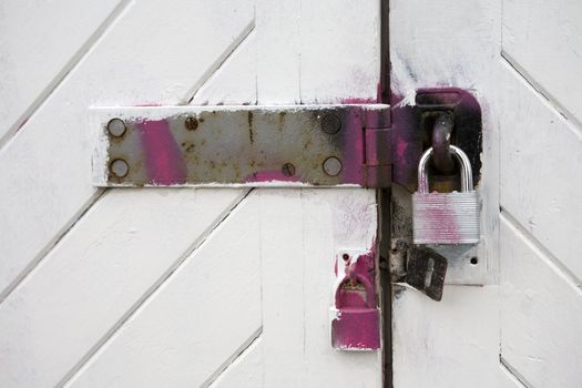 Fragment of door with steel lock hanging on house