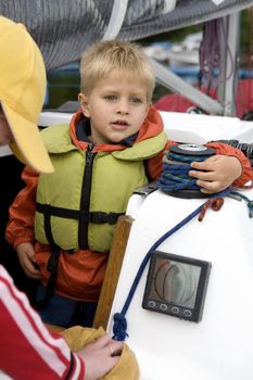 Little cute boy five years old  in life jacket on yacht. Summer time