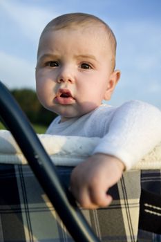 portrait of little cute boy six month old sitting on buggy. Park