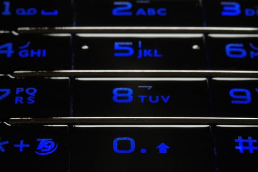 Close up shot of blue mobile keypad under dark environment