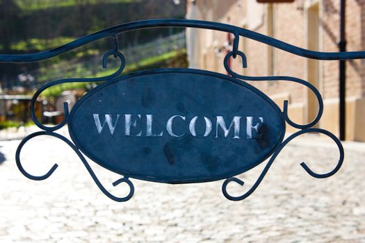 An old hanging welcome sign in Italy, rustic building