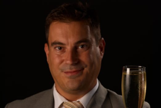 Man toasting with a glass of champagne, focus on glass