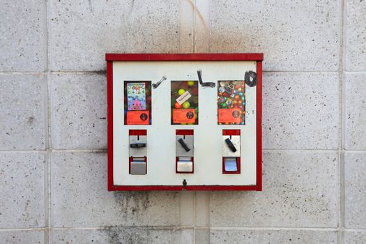 a bit dirty gumball/candy vending machine on a wall