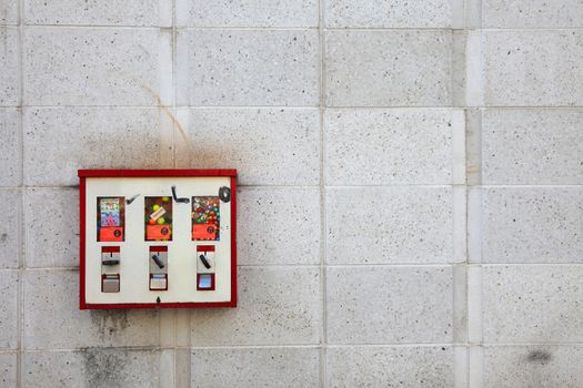 a bit dirty gumball/candy vending machine on a wall