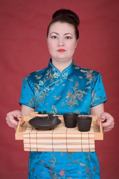 Japanese girl with tea-tray on the red background