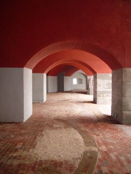 A hallway of repeating red and white arches.