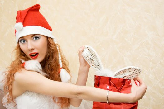 Surprised redhead girl dressed as Santa Helper with christmas gift