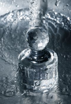 Glass bottle of perfumery in water with drops