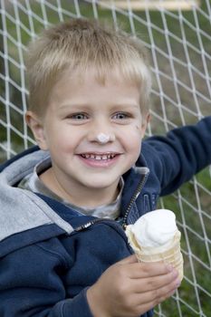 little cute boy eating ice-cream sitting in hammock. Summer time