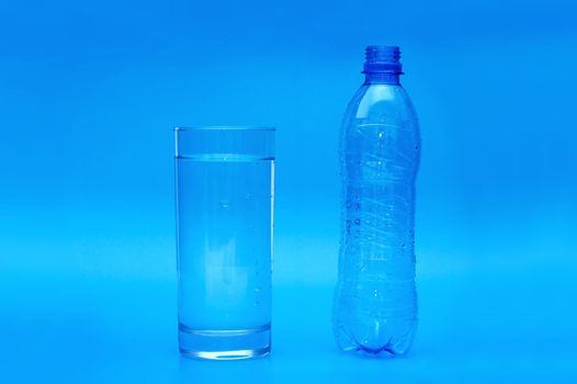 Full glass and empty bottle on blue background
