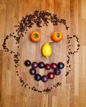face made of fruits on wooden background
