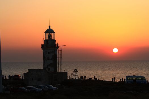 people watching the sunset near a lighthouse