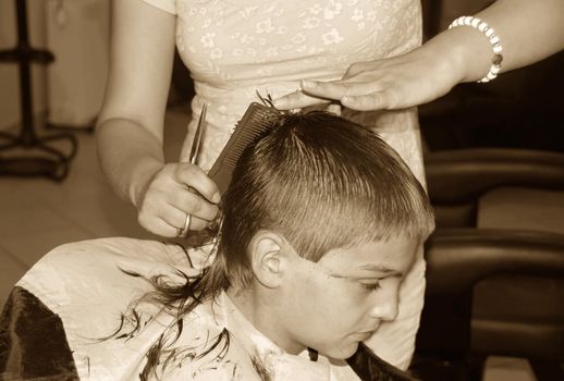 caucasian boy getting a haircut sepia tones