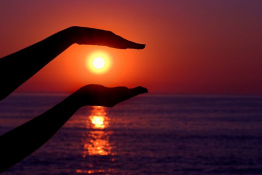 Female hands silhouette holding the sun 