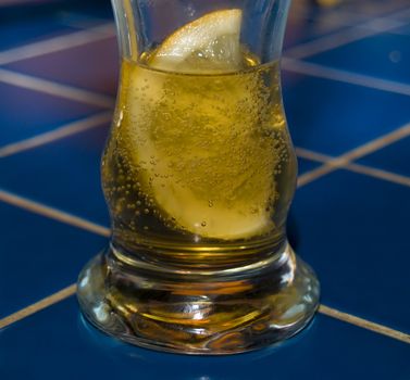 Glass with beer and slice of lemon on a table in bar