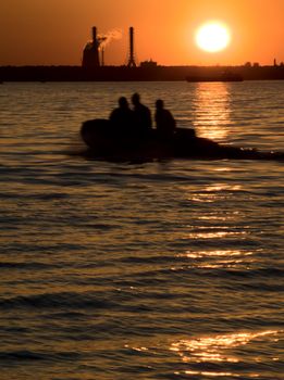 Three peoples rowing in city at sunset