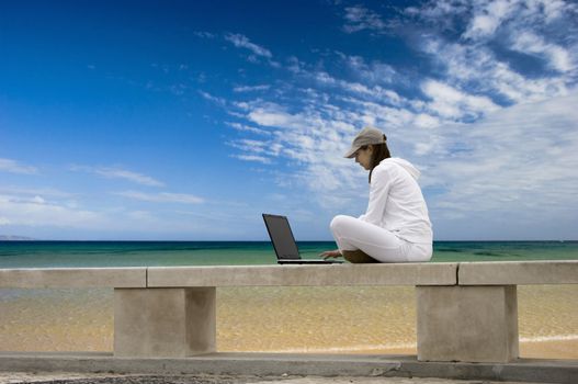 Woman working with a laptop sitting in a wall with a great view over a beautiful green meadow