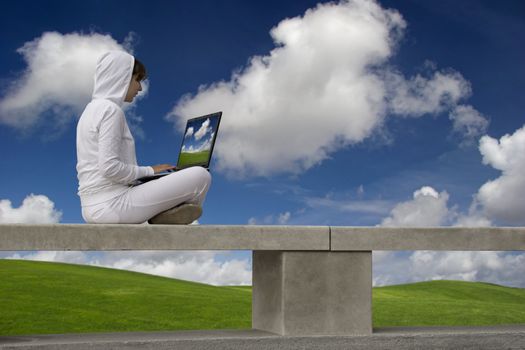 Woman working with a laptop sitting in a wall with a great view over a beautiful green meadow