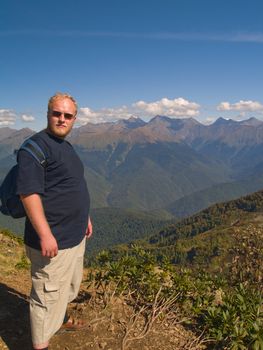 Adult man with backpack on the top of the mountain