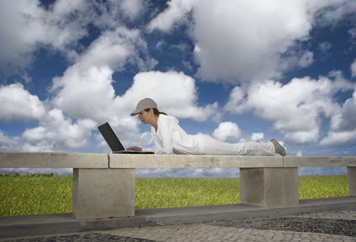 Woman working with a laptop sitting in a wall with a great view over a beautiful green meadow