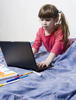 Cute little girl seven years old playing with computer