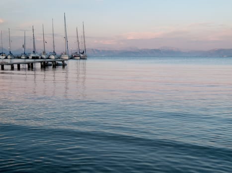 Sunset over the calm waters of the mediterranean with yachts tied up at the dock