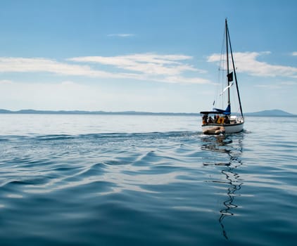 Yacht with trailing dinghy on the calm seas of the Mediterranean