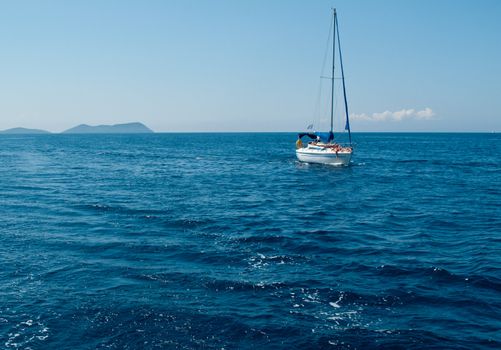 People sunbathing on deck of sailboat on the calm seas