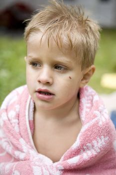 little cute boy five years old muffled in towel after he swam in river