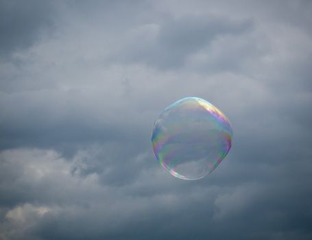 Soap bubble floating against a cloudy and stormy sky