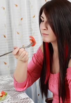 caucasian girl holding a fork, ready to eat a piece of tomato