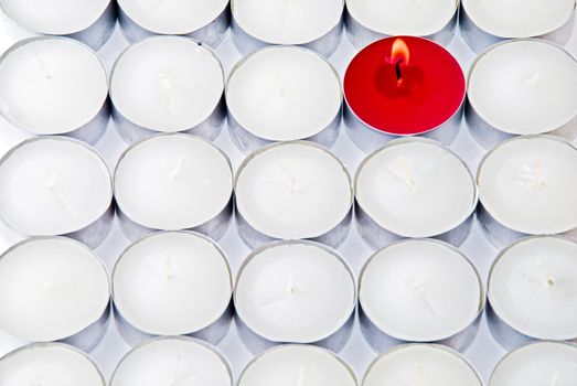 One red candle among lots of white candles