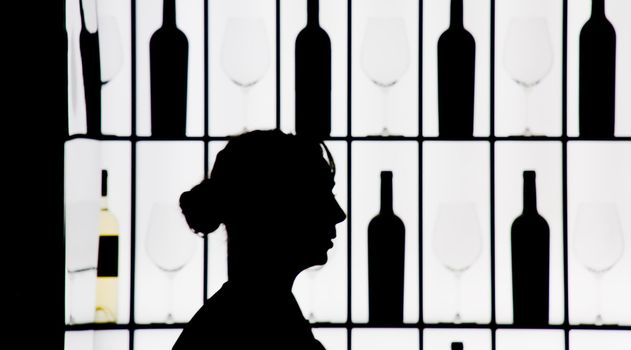 Silouette of a waitress against bottle and glasses