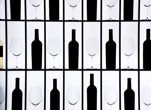 Black bottles and crystal glasses decorate a wall creating a motif