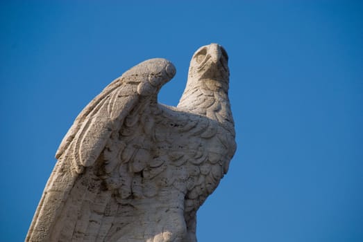 Old statue of an eagle on a blue sky in Rome, Italy .