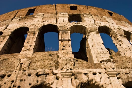 Low Angle view of the Colosseum Amphitheater in Rome against blue sky background.